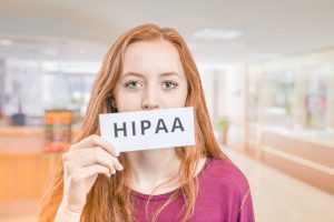 An Image of a redhead female holding a sign with the word HIPAA. Ensuring HIPAA Compliance for Healthcare